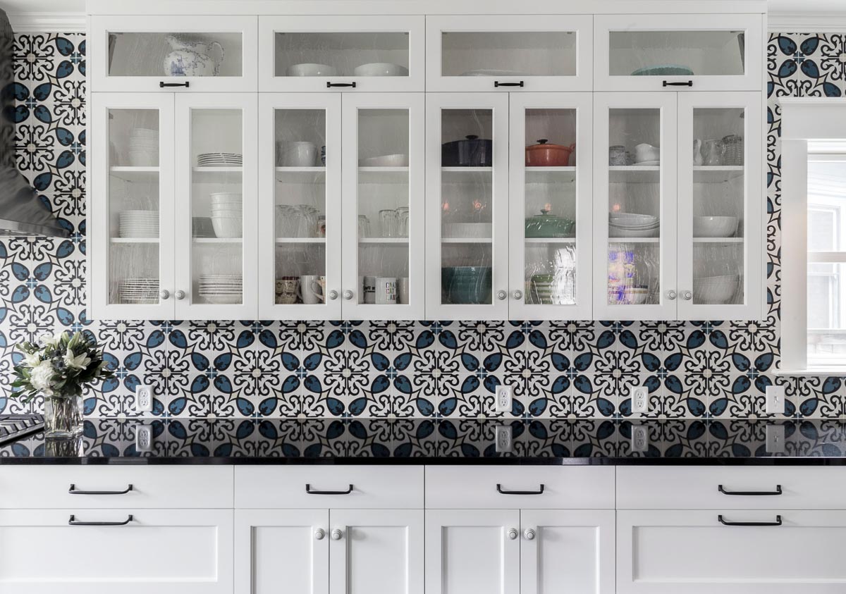 beautiful glass cabinets with china and dishes inside and a black countertop below in a kitchen